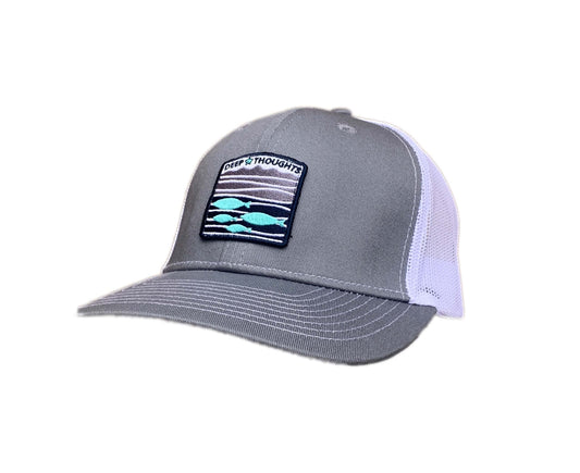 Grey and white trucker cap with embroidered blue white and grey fish under waves patch